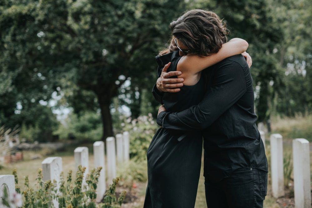 A Man is Hugging a Woman in a Cemetery — Becker Family Funerals In Old Bar, NSW