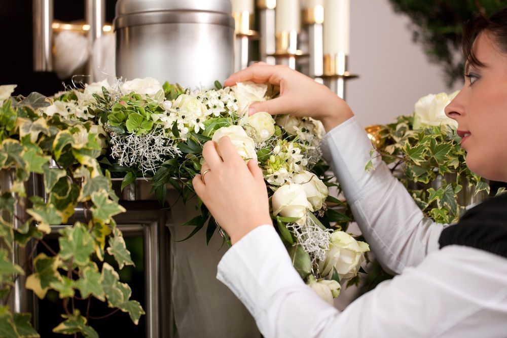 A Woman is Arranging Flowers in Front of a Candle Holder — Becker Family Funerals In Forster, NSW