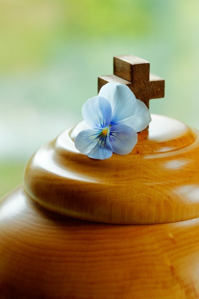 A Wooden Urn With a Blue Flower and a Cross on Top — Becker Family Funerals In Taree, NSW
