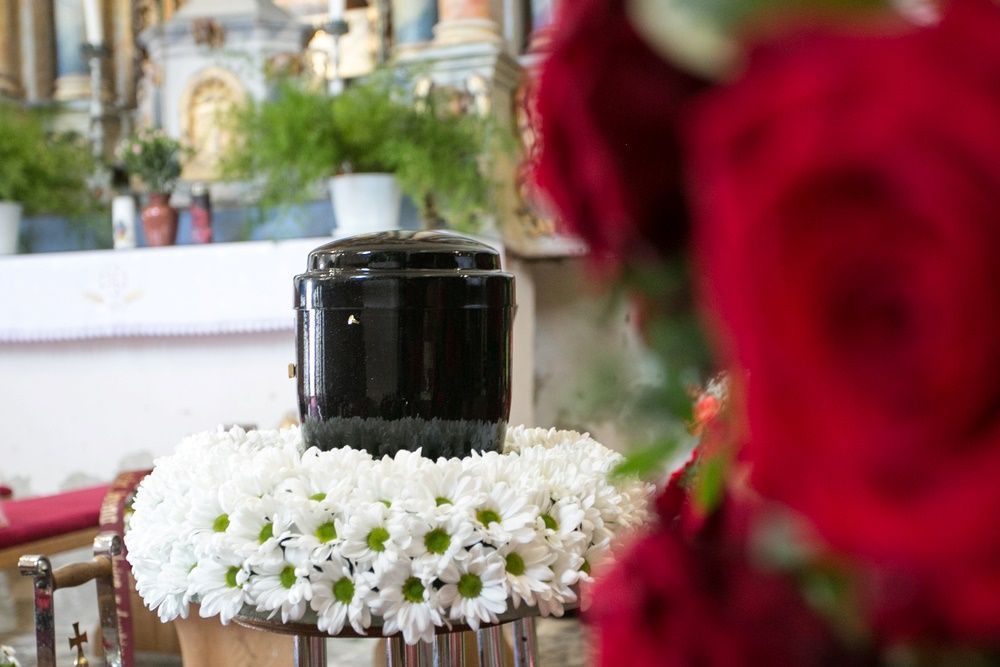 A Black Urn Surrounded by White Flowers — Becker Family Funerals In Forster, NSW