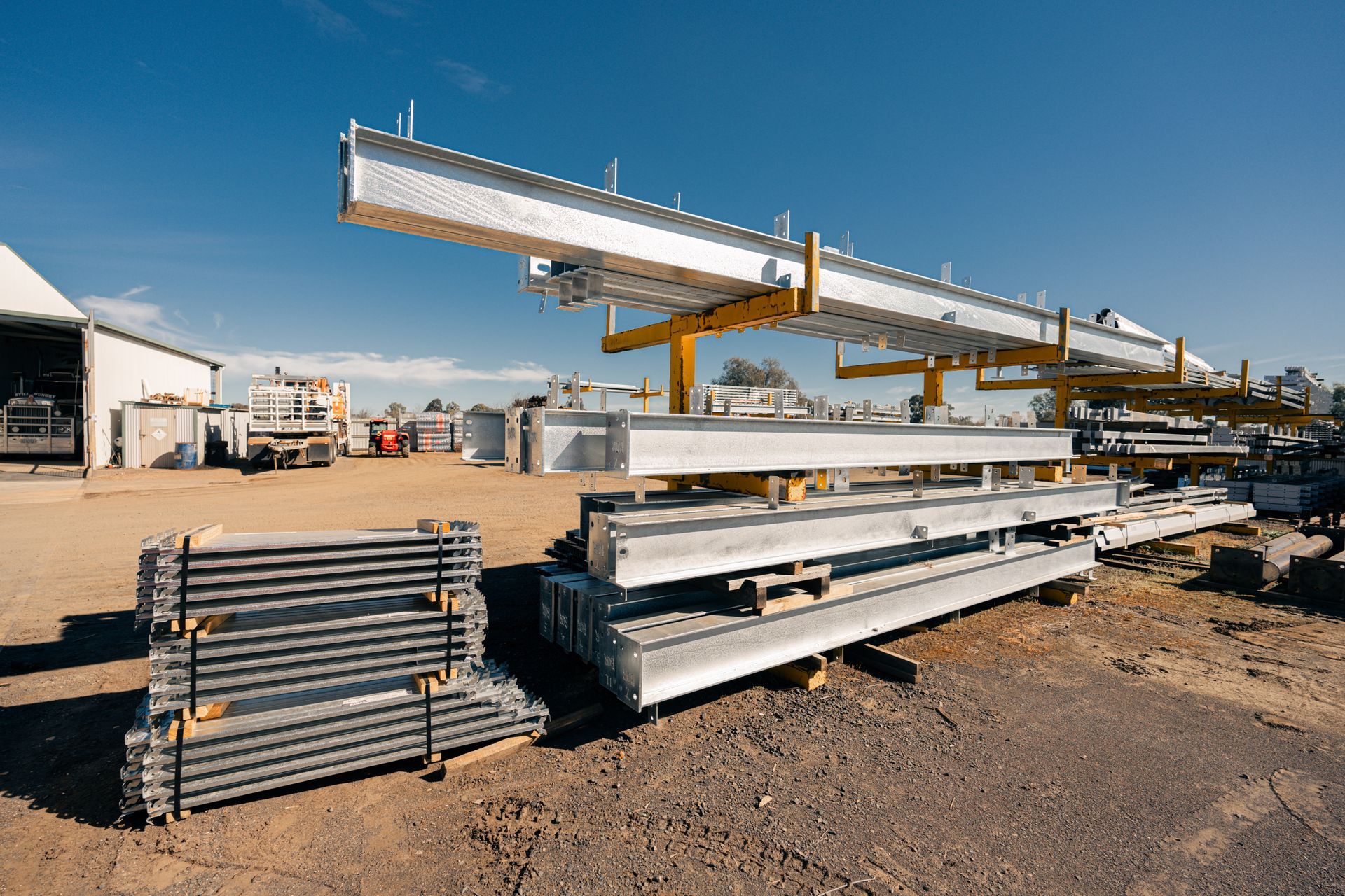 A bunch of metal beams are stacked on top of each other in a yard.