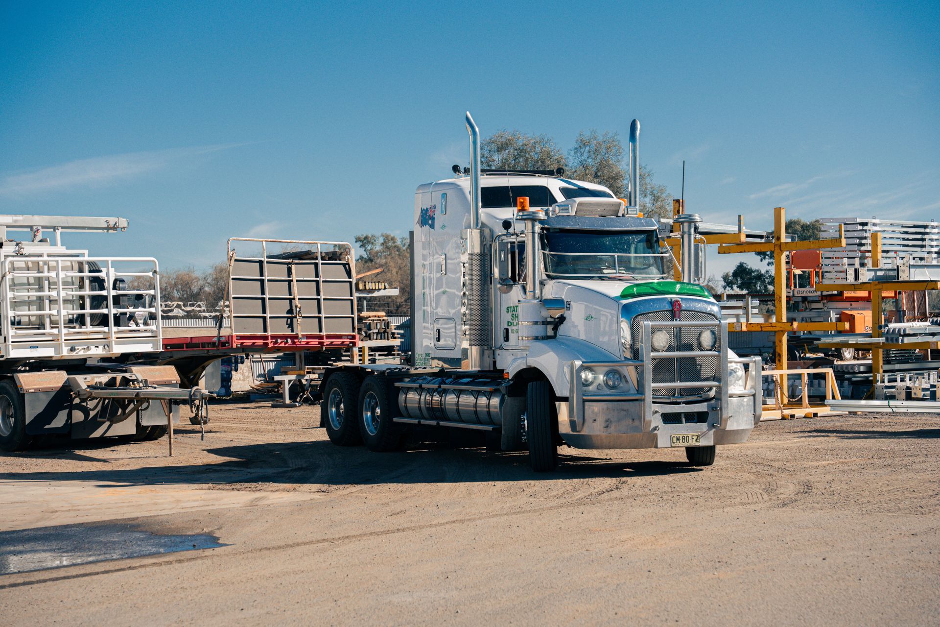 A semi truck is parked in a dirt lot.