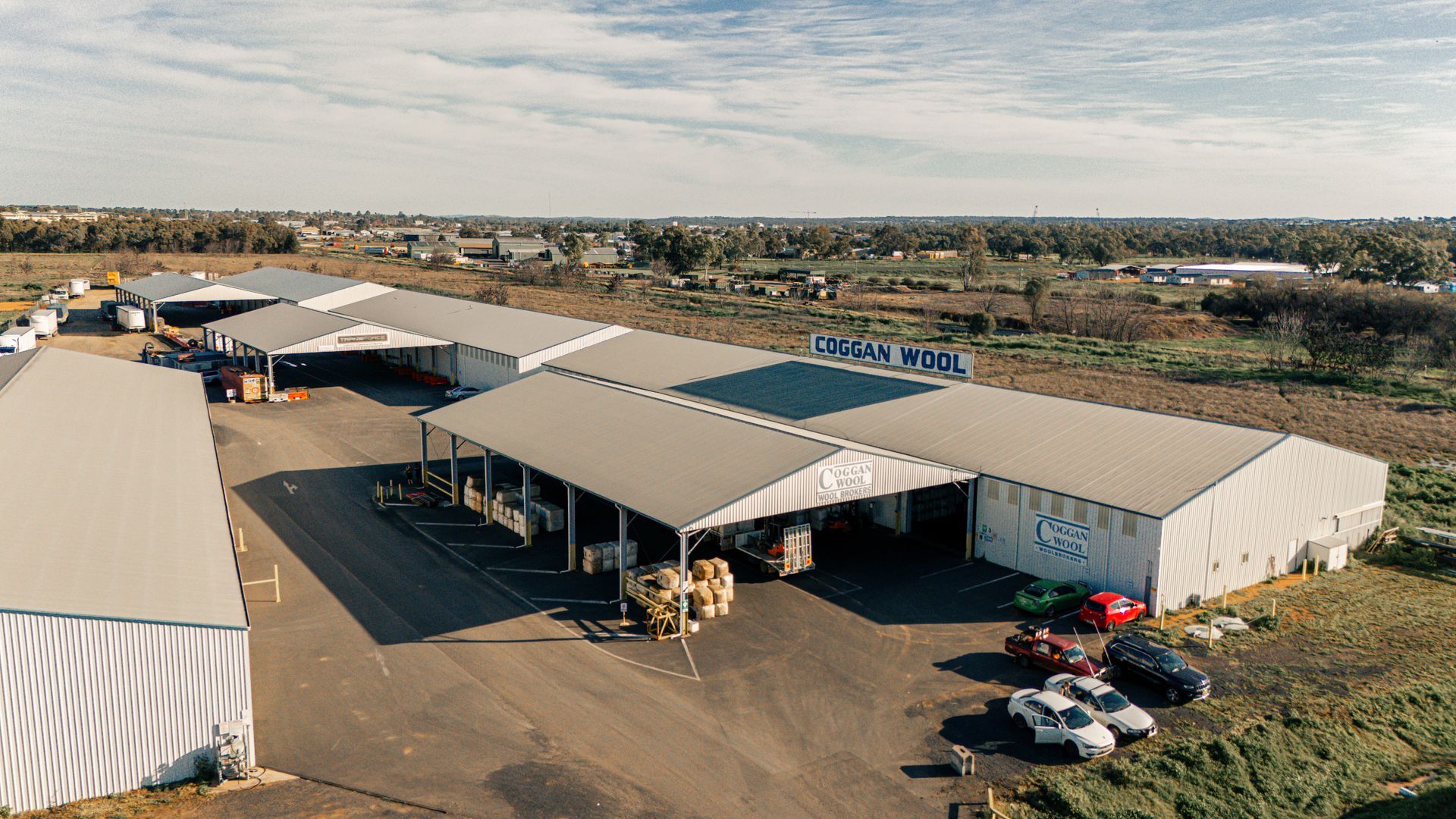 An aerial view of a large warehouse with a lot of cars parked in front of it.