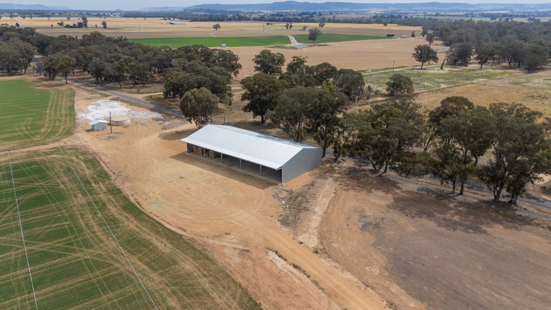 A large white building is sitting in the middle of a dirt field.