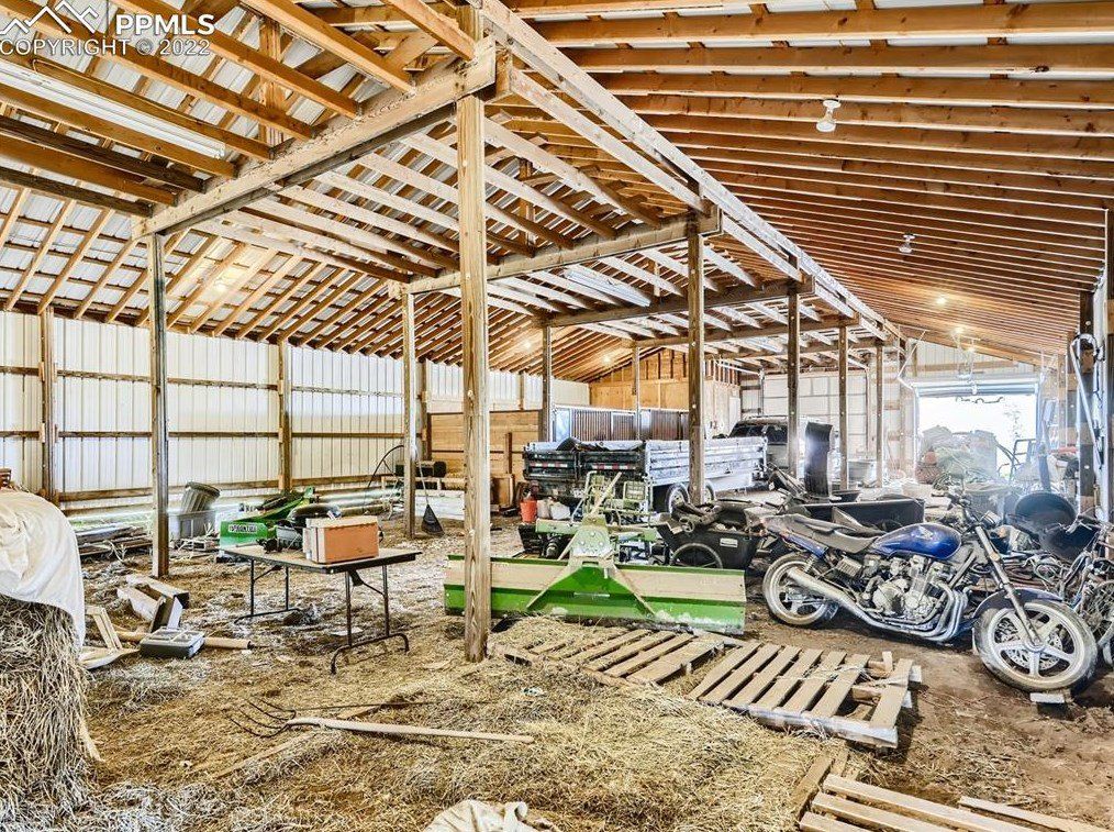 A barn filled with lots of machinery and motorcycles.