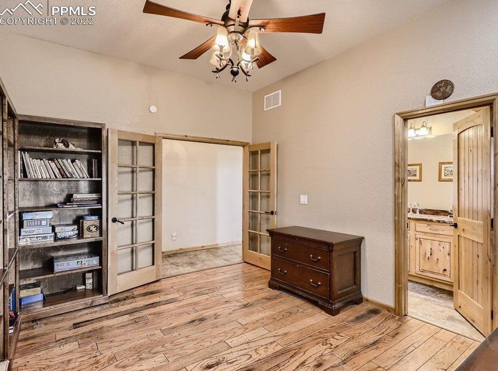 A bedroom with hardwood floors and a ceiling fan.