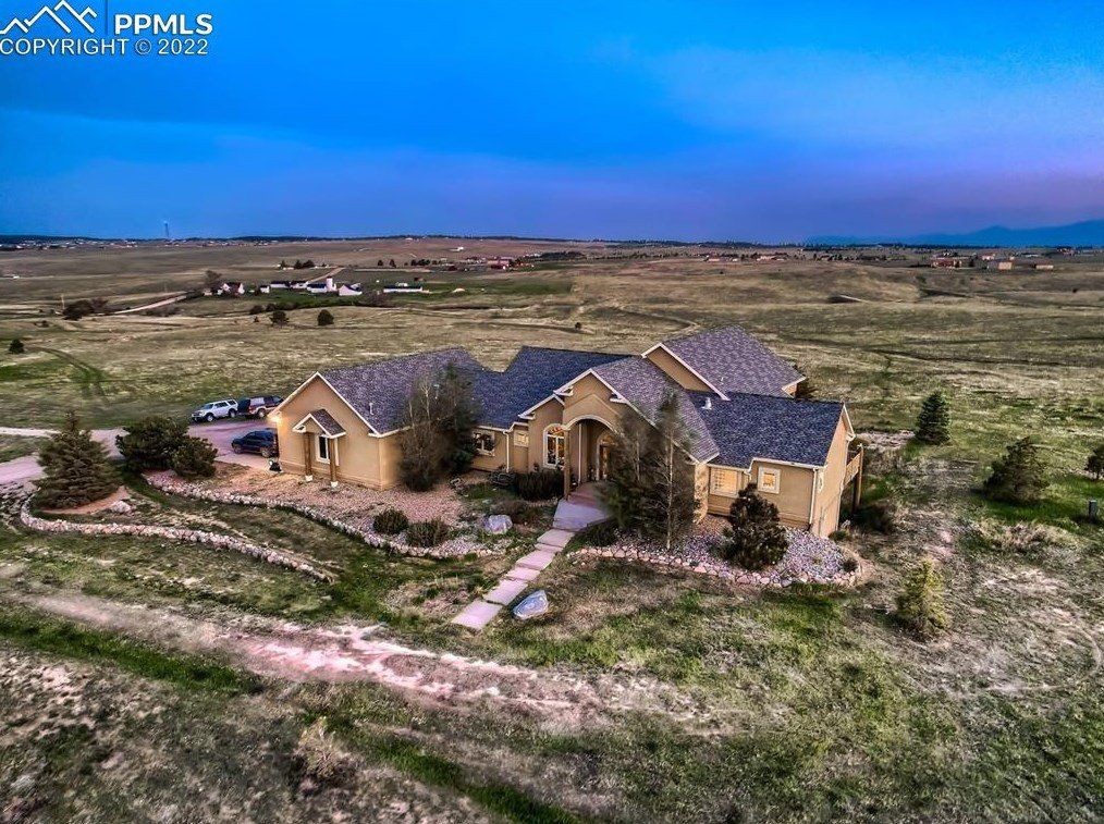 An aerial view of a large house in the middle of a field.