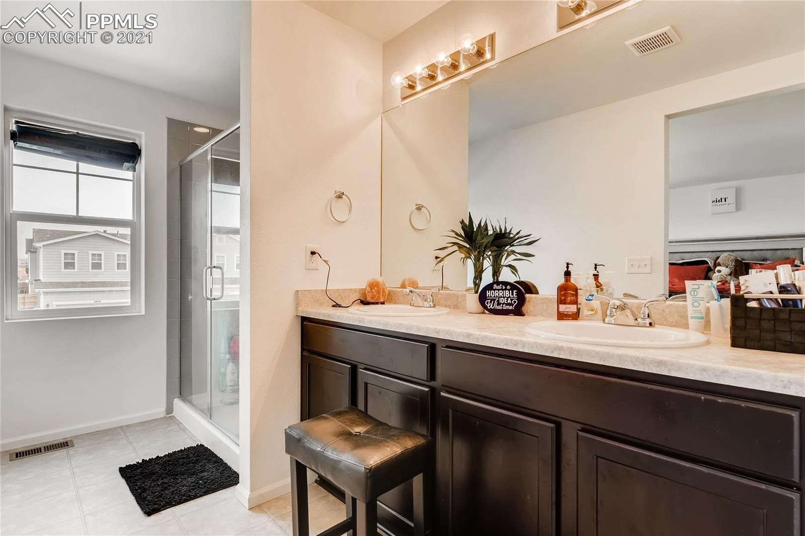 A bathroom with two sinks , a mirror and a stool.