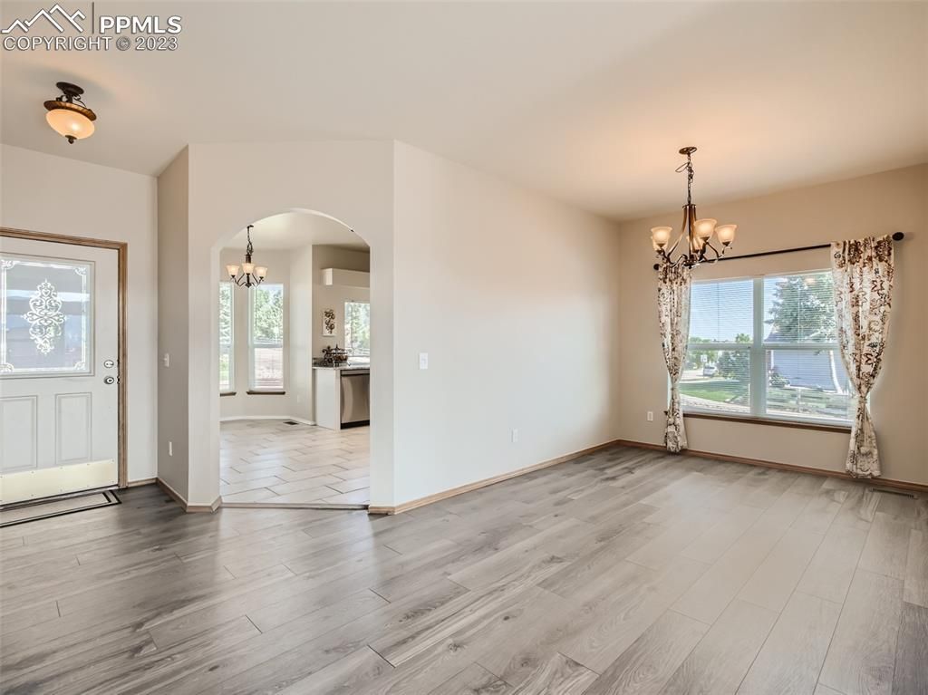 An empty living room with hardwood floors and a chandelier