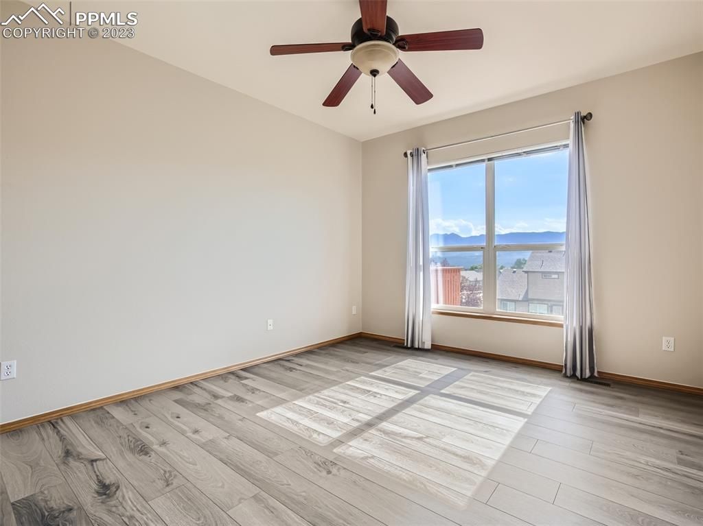 A bedroom with a ceiling fan and a large window