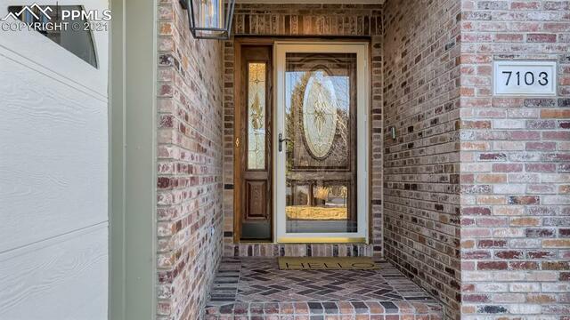 The front door of a house with a brick wall and a glass door.
