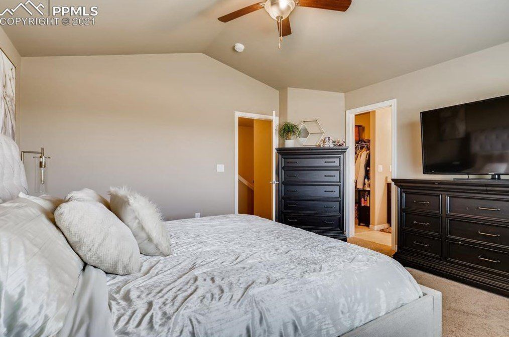 A bedroom with a bed , dresser , television and ceiling fan.