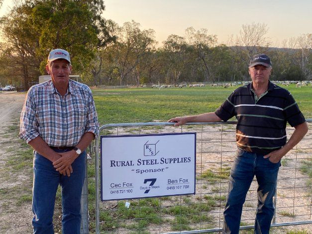 Two persons standing at rural steel supplies gate