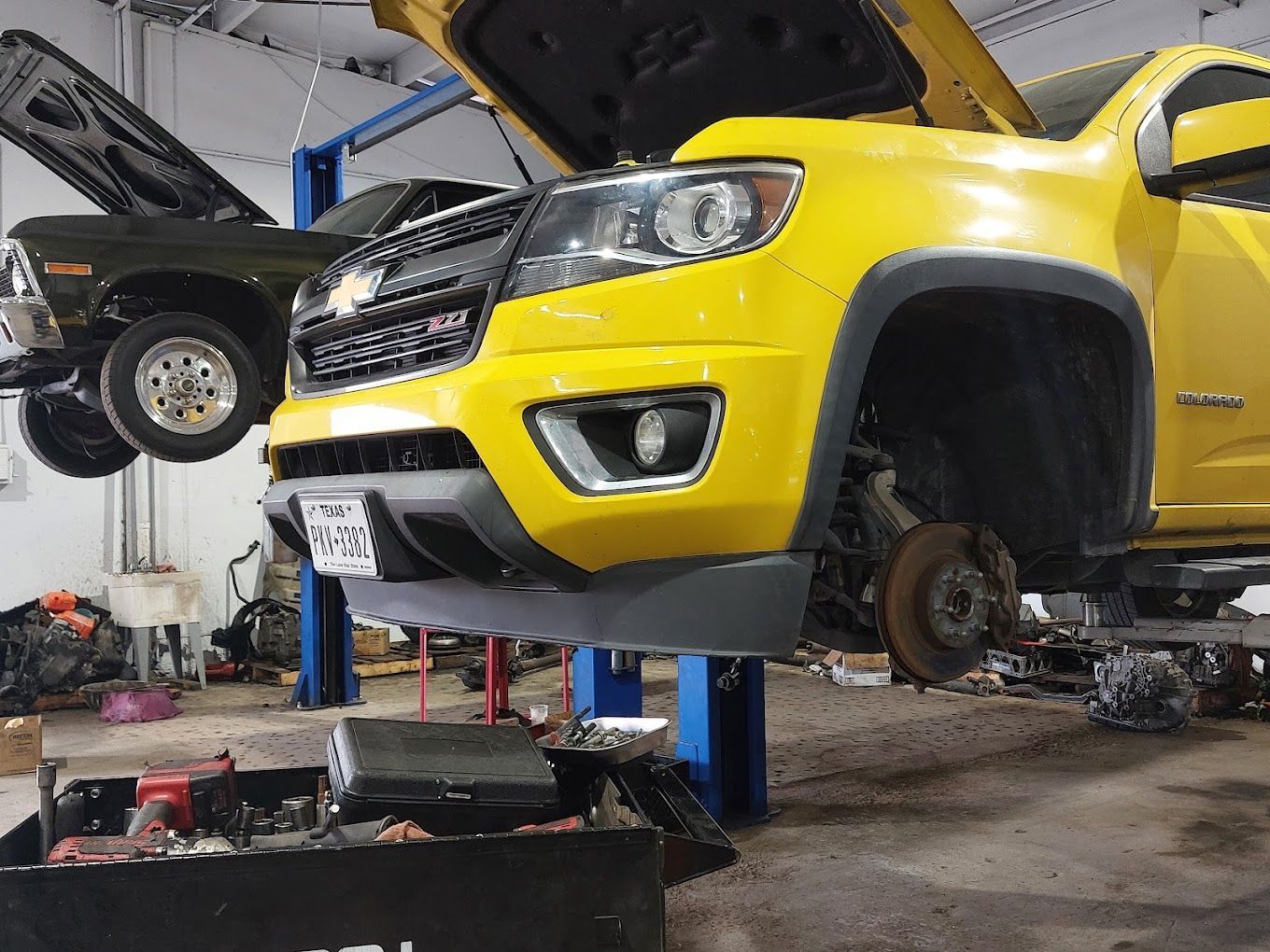 A yellow truck is sitting on a lift in a garage.