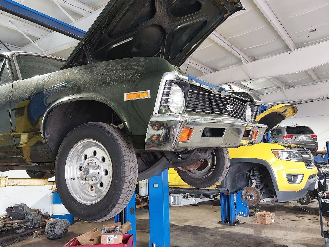 A green car is sitting on a lift in a garage.