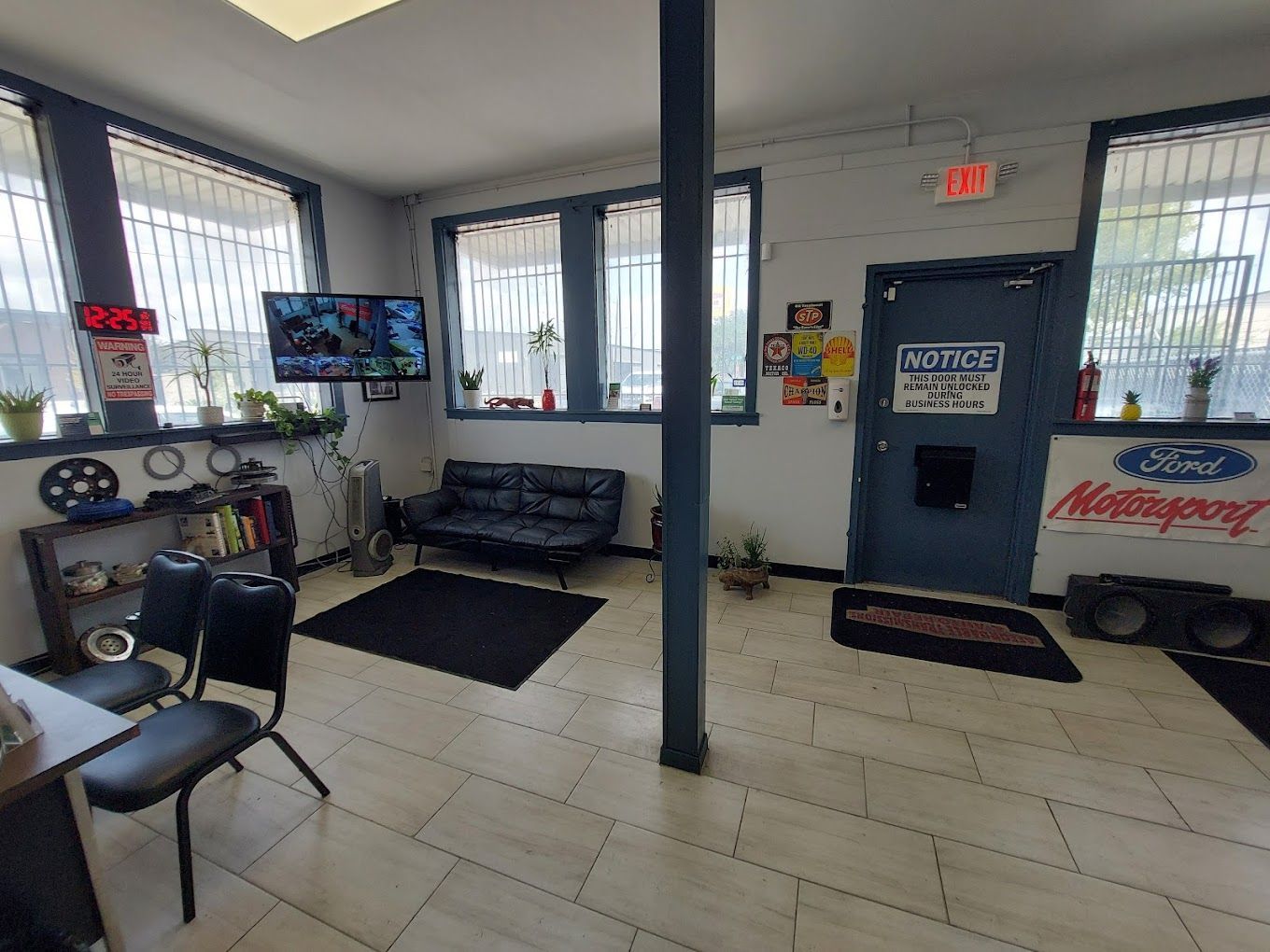 A waiting room with a couch , chairs , and a sign that says ford motorsports.
