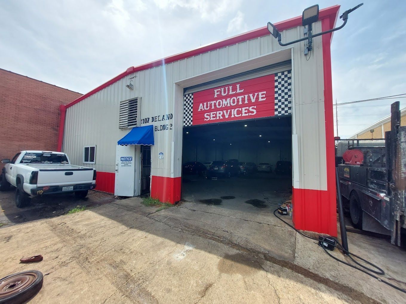 A white truck is parked in front of a full automotive services building.