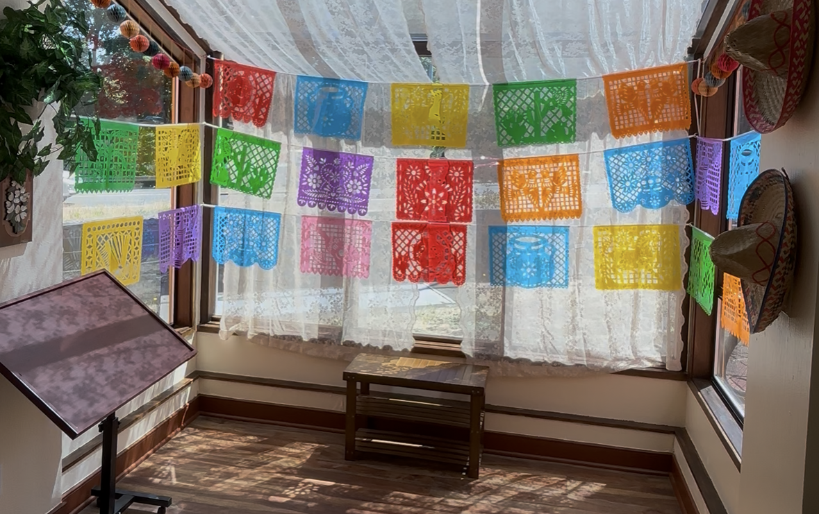 A room with a lot of colorful paper flags hanging from the ceiling.