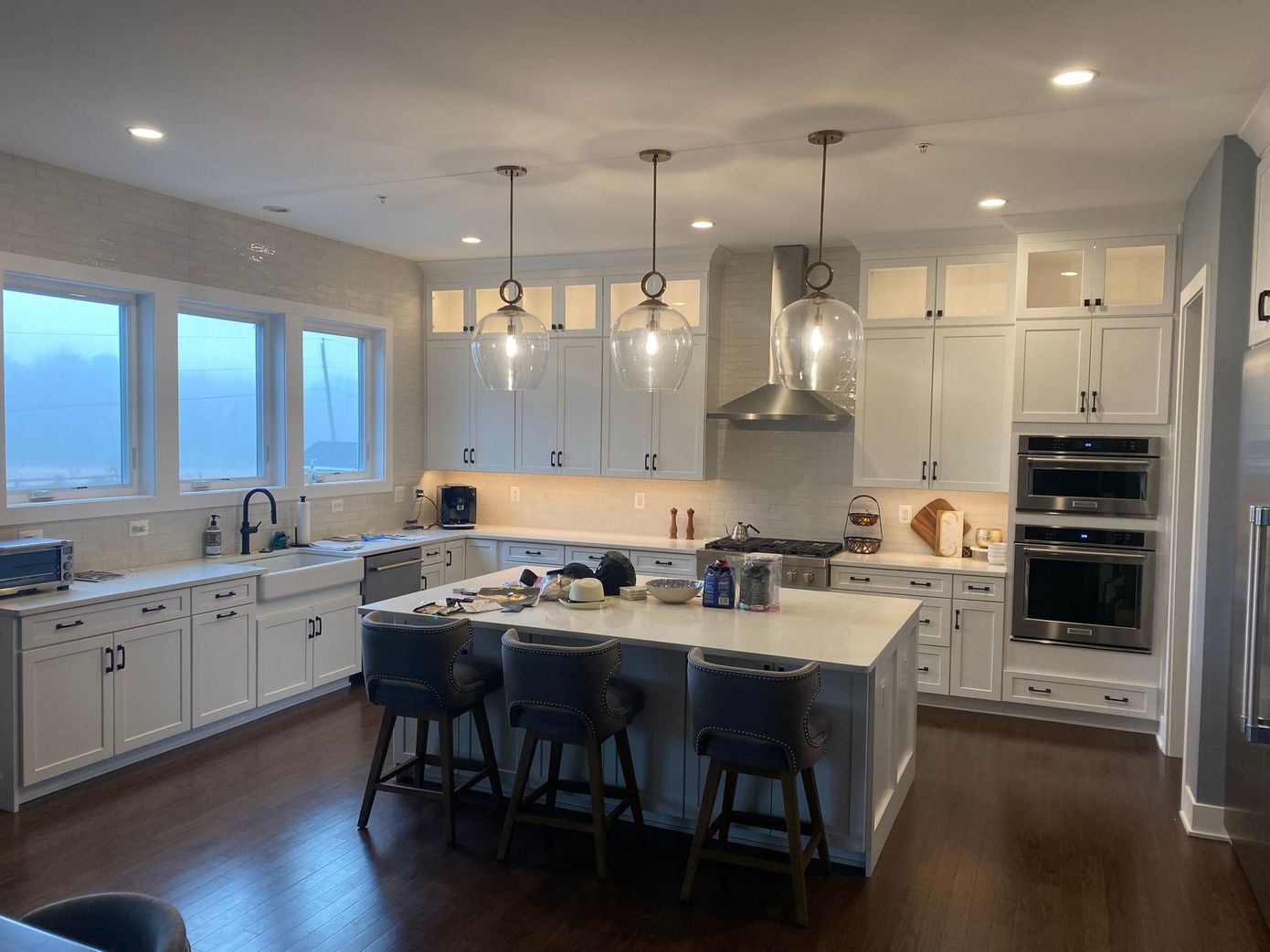 A large kitchen with white cabinets , stainless steel appliances , and a large island.