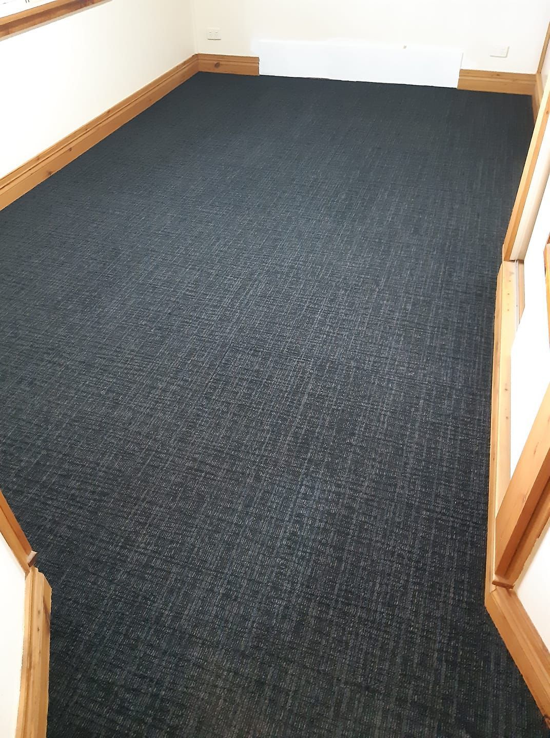 A black carpeted floor in a room with stairs