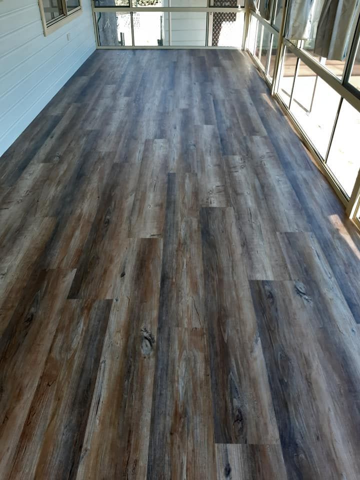 A large room with a wooden floor and lots of windows