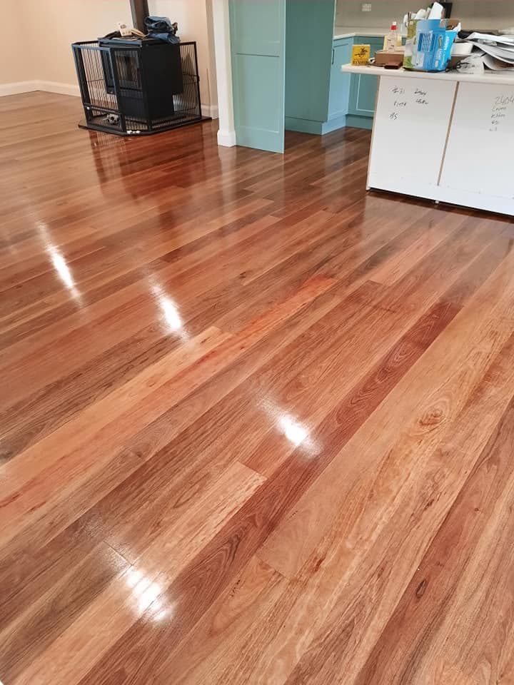 A wooden floor in a kitchen with a wood stove in the background