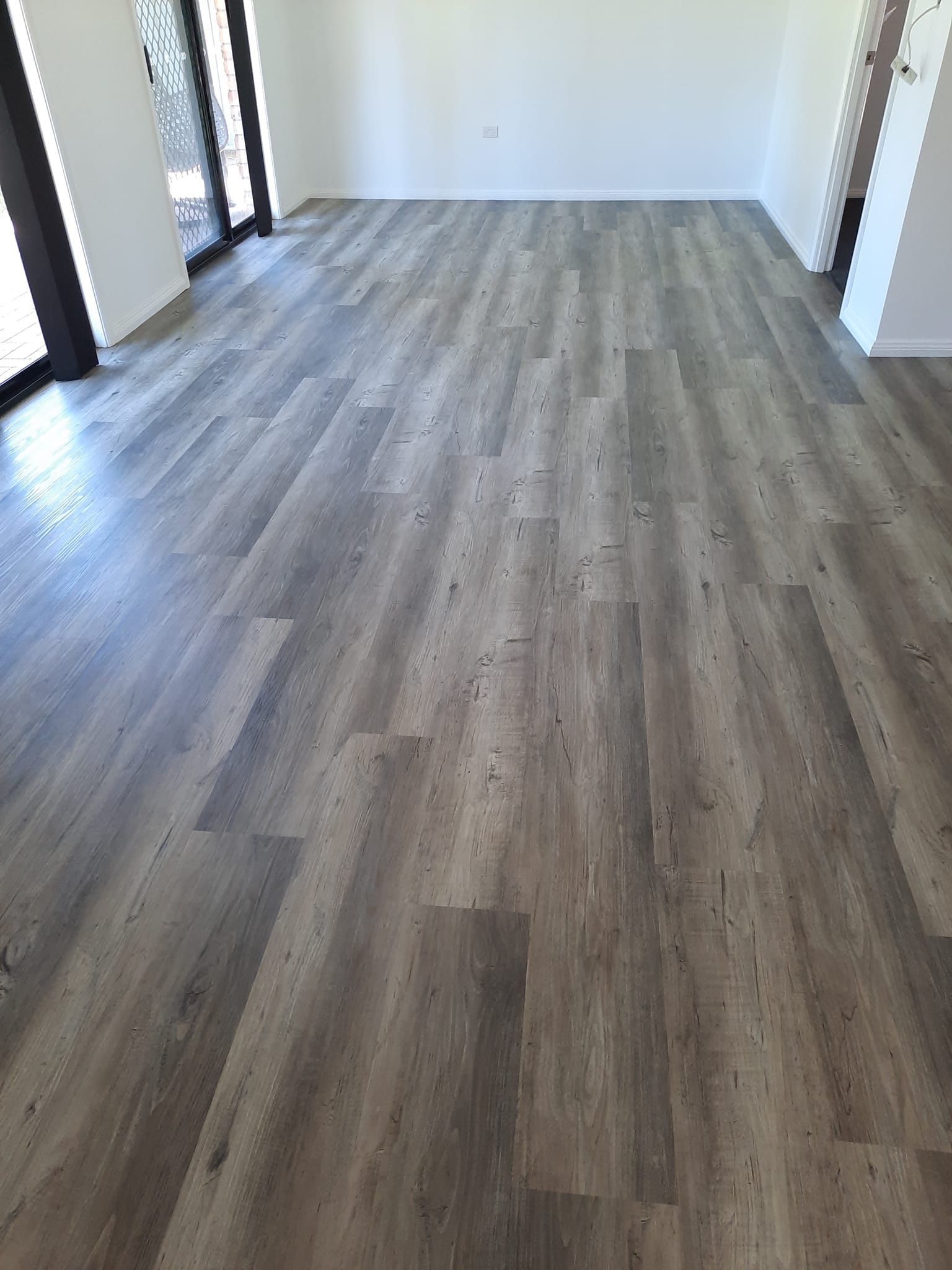 A living room with a wooden floor and sliding glass doors