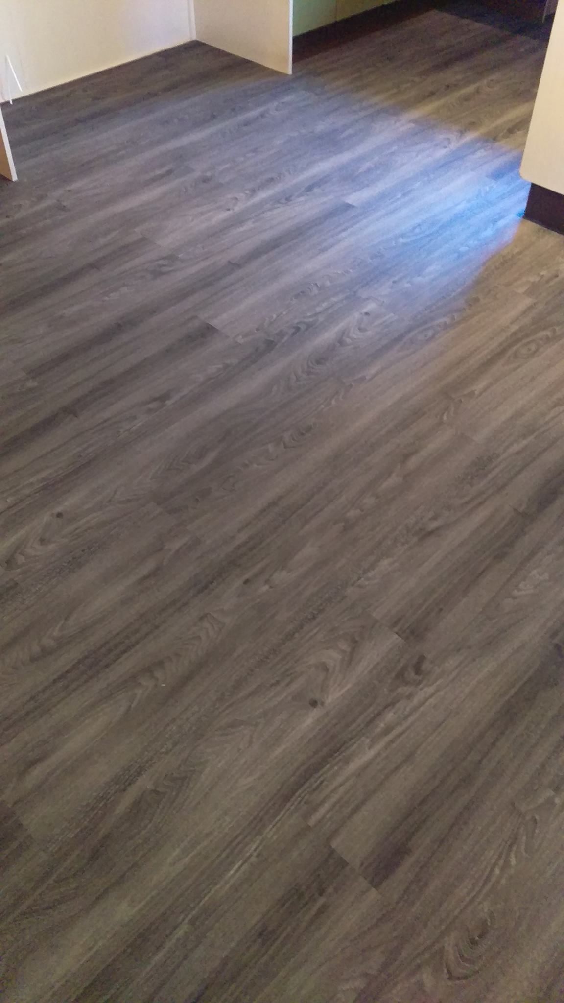 A room with a gray wooden floor and stairs