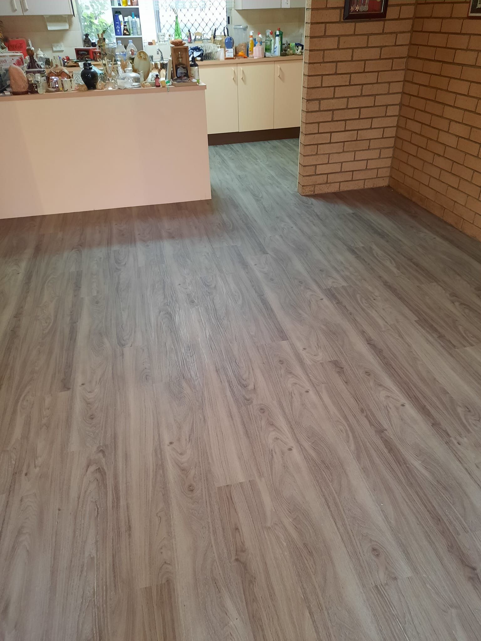 A kitchen with a wooden floor and a brick wall
