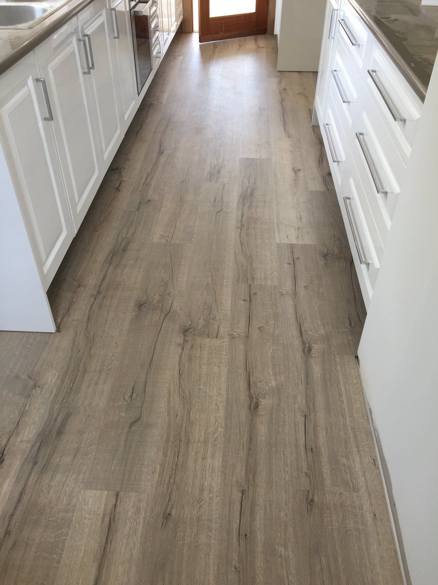 A kitchen with a wooden floor and white cabinets