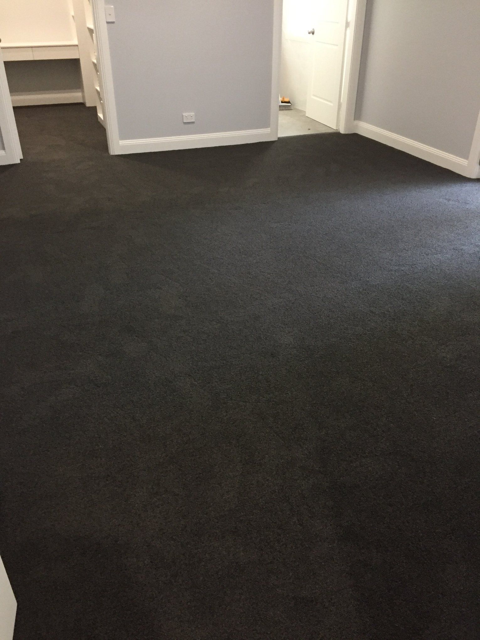 A room with a black carpeted floor and a door