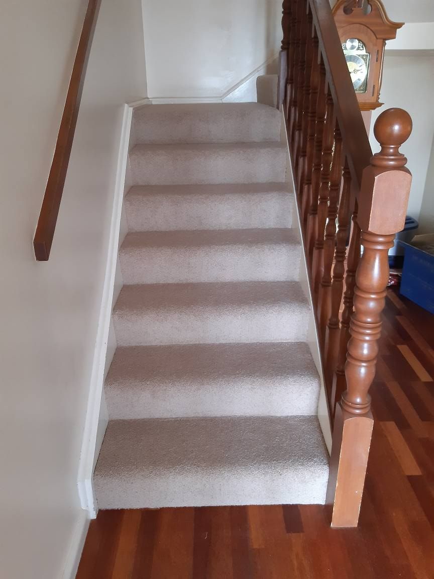 A staircase with a wooden railing and a clock on the wall