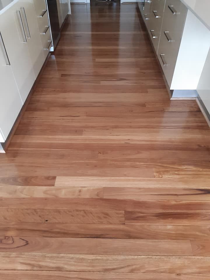 A kitchen with hardwood floors and white cabinets
