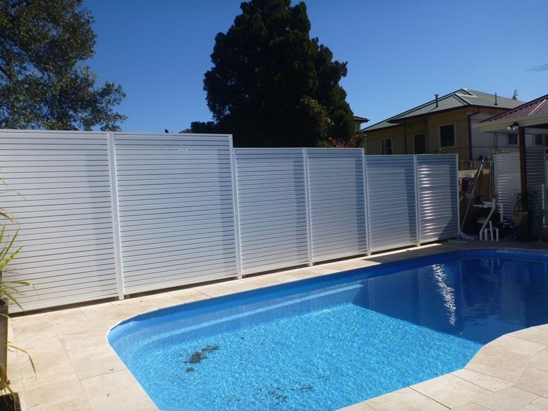 A large swimming pool with a white fence around it