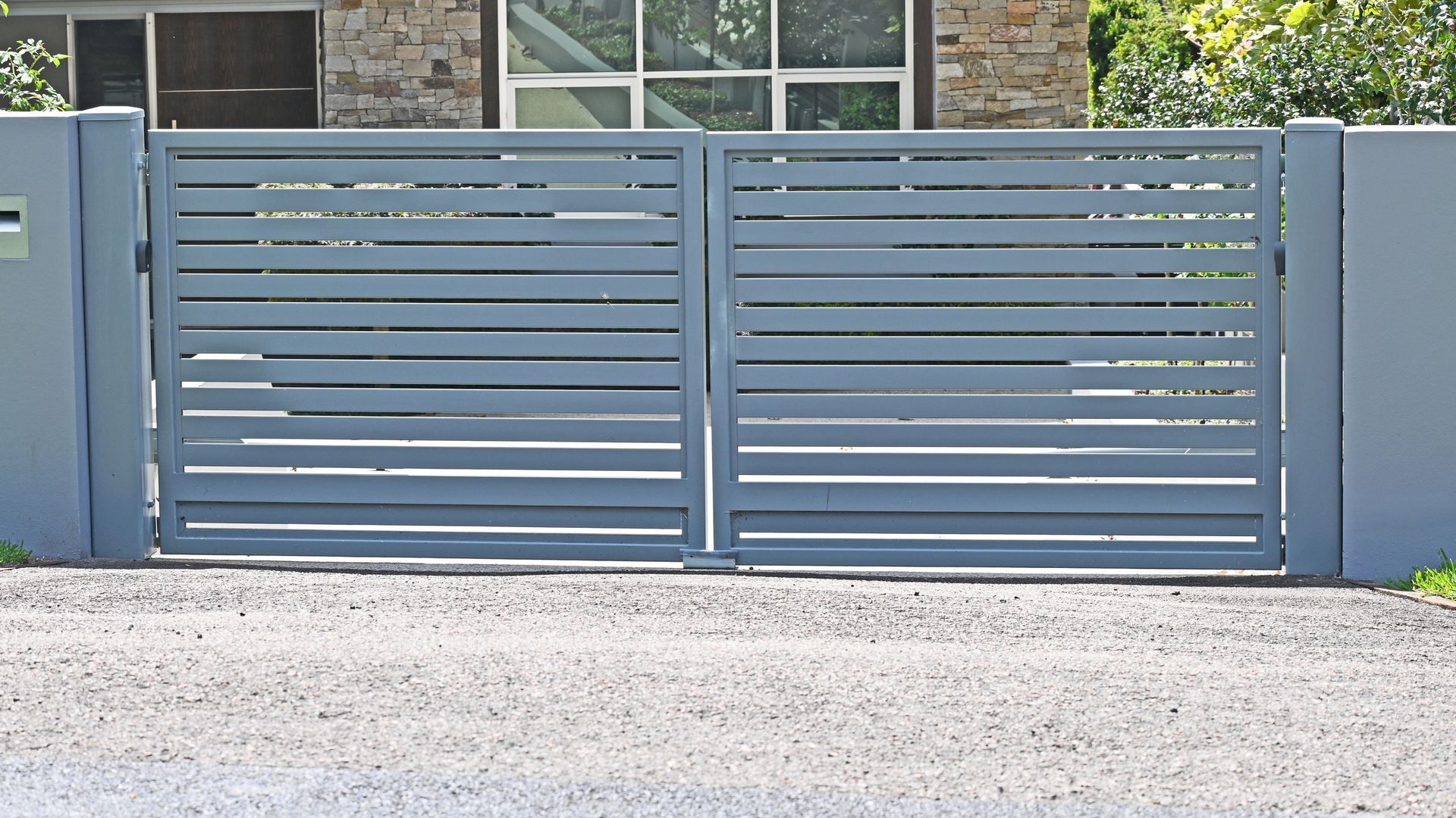 Custom aluminium front gate with horizontal slats installed at a residential entrance. Custom aluminium front gate with horizontal slats installed at a residential entrance.