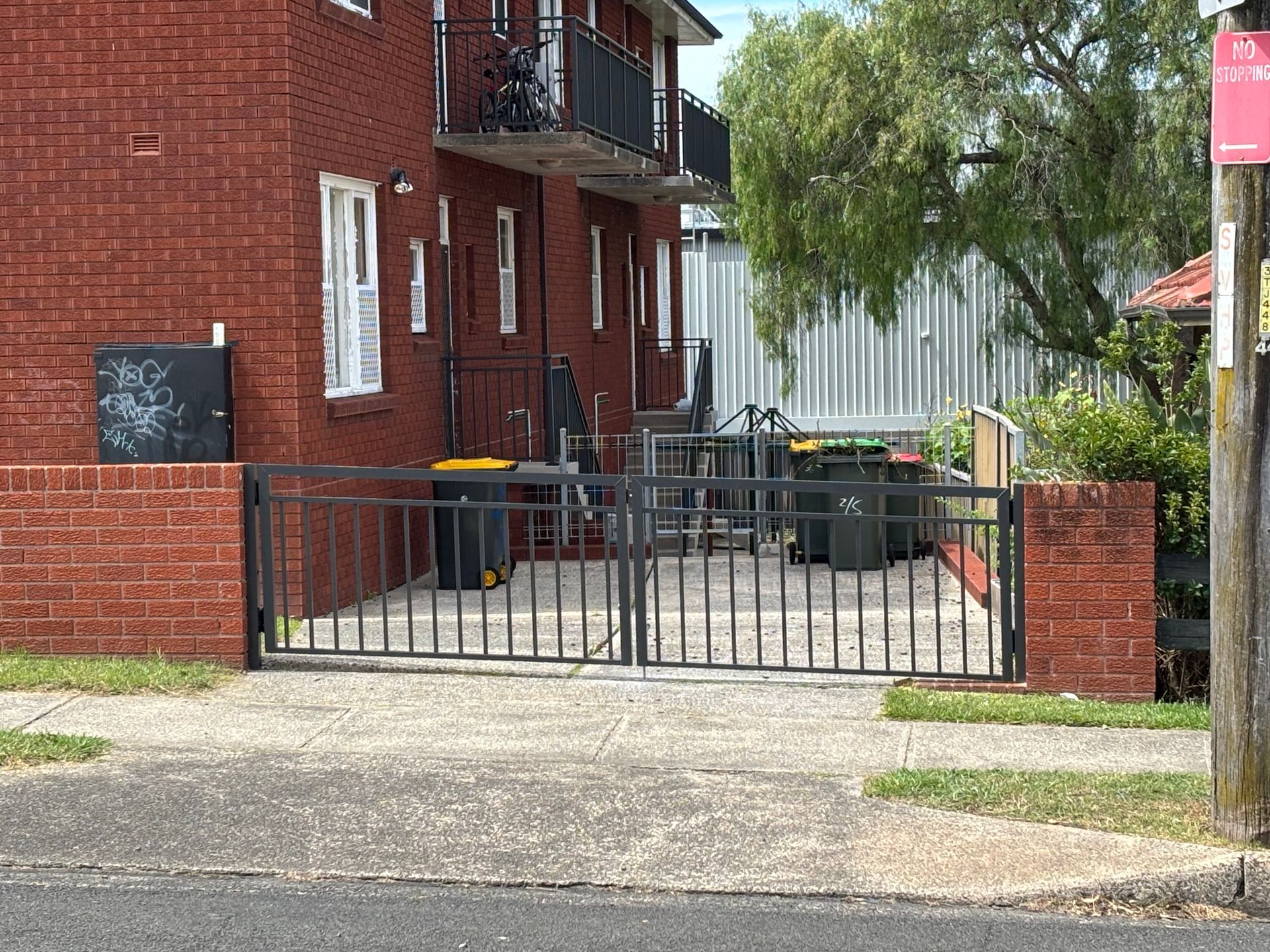 A red brick building with a black gate in front of it.