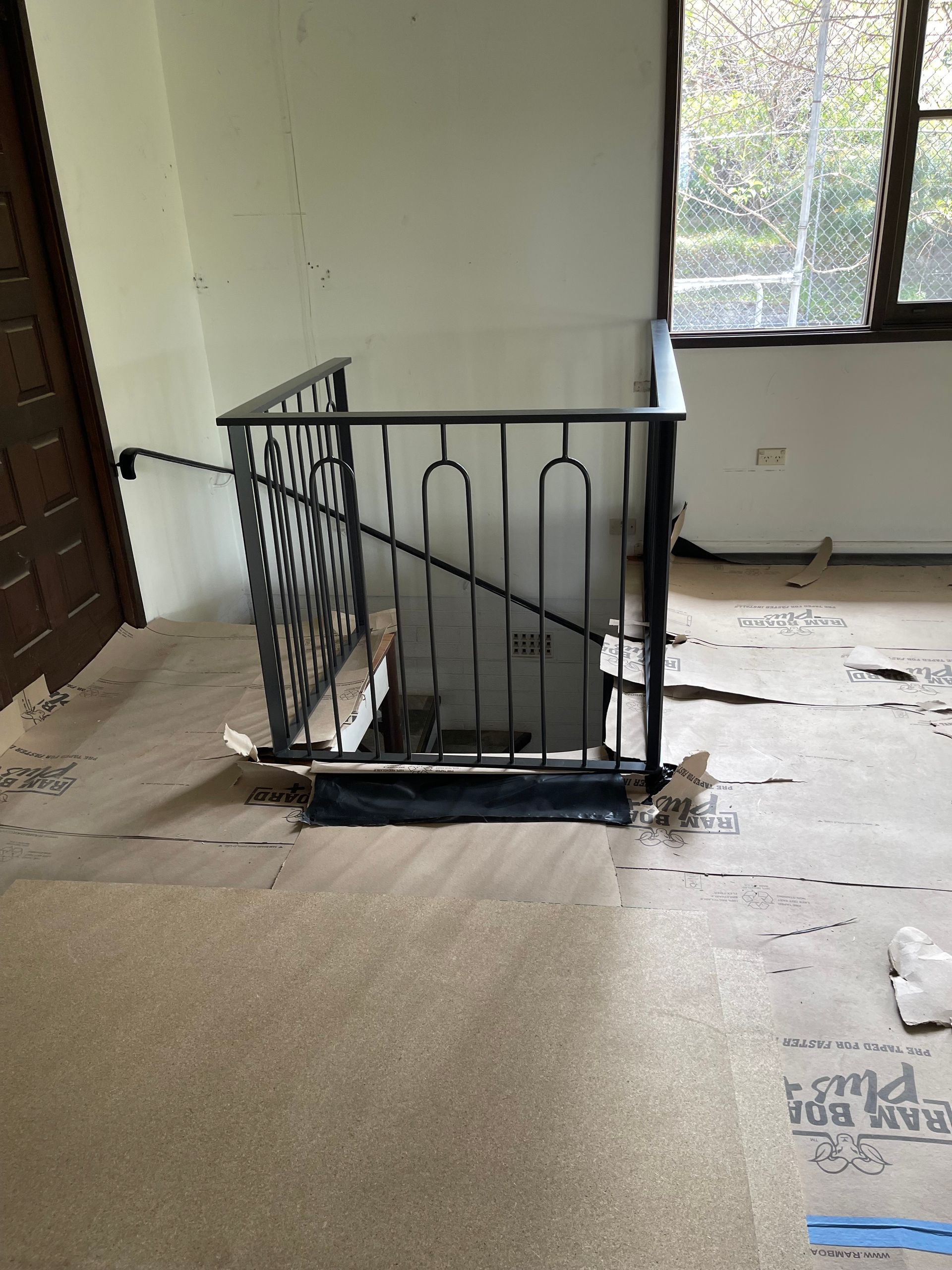 A staircase with a wrought iron railing in a room with a window.