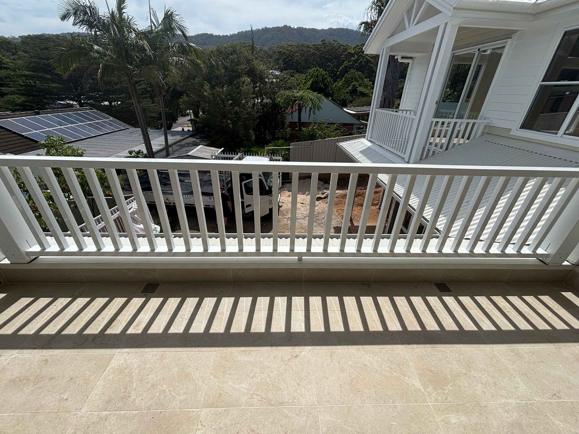A balcony with a white railing and a view of a house.