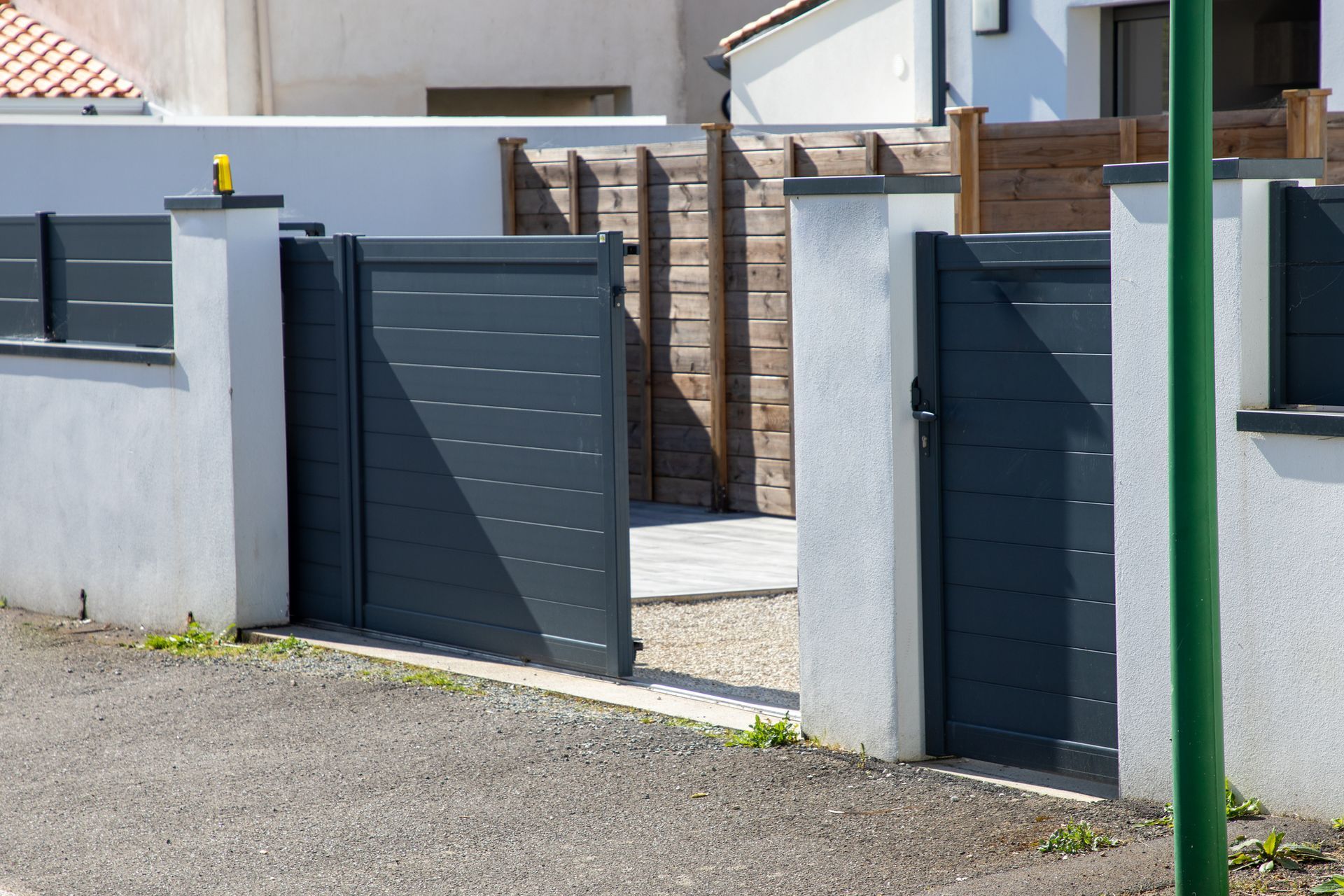 Modern gray gate and fence at the entrance of a residential property.
