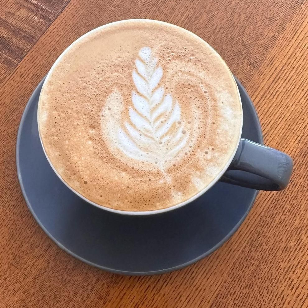 A Cup of Cappuccino on a Saucer on a Wooden Table — Labroco Gourmet Coffee Supplier In Port Macquarie, NSW