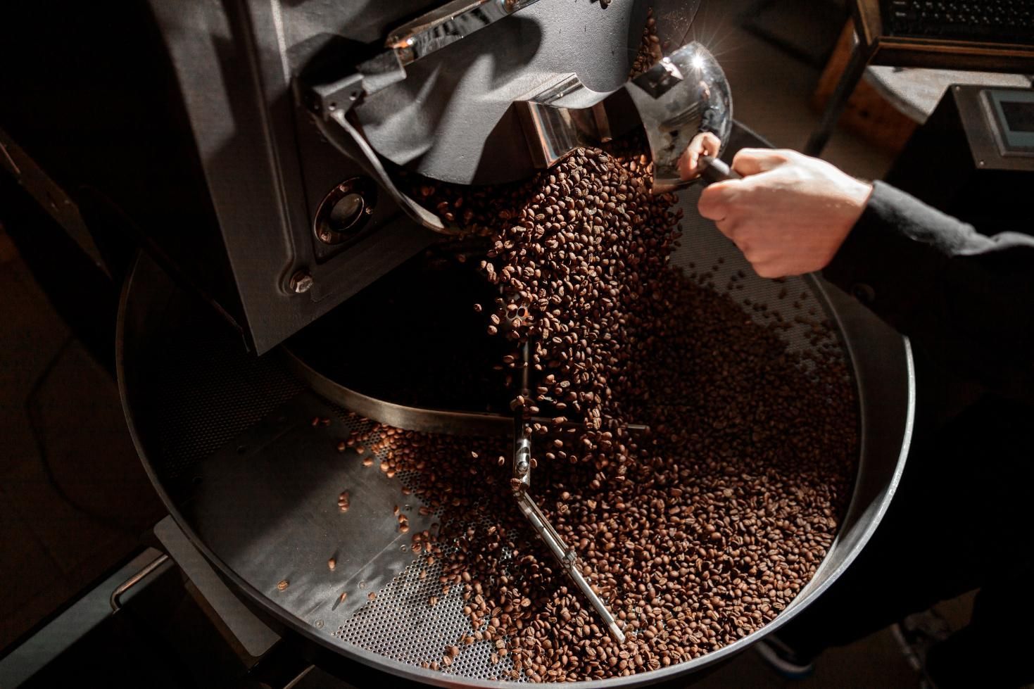 A Person is Pouring Coffee Beans Into a Roasting Machine — Labroco Gourmet Coffee Supplier In Diamond Beach, NSW