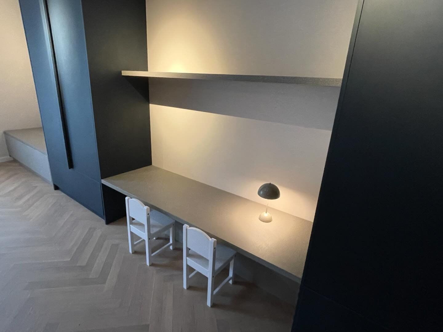 Een bureau met twee stoelen en een lamp in een kamer.