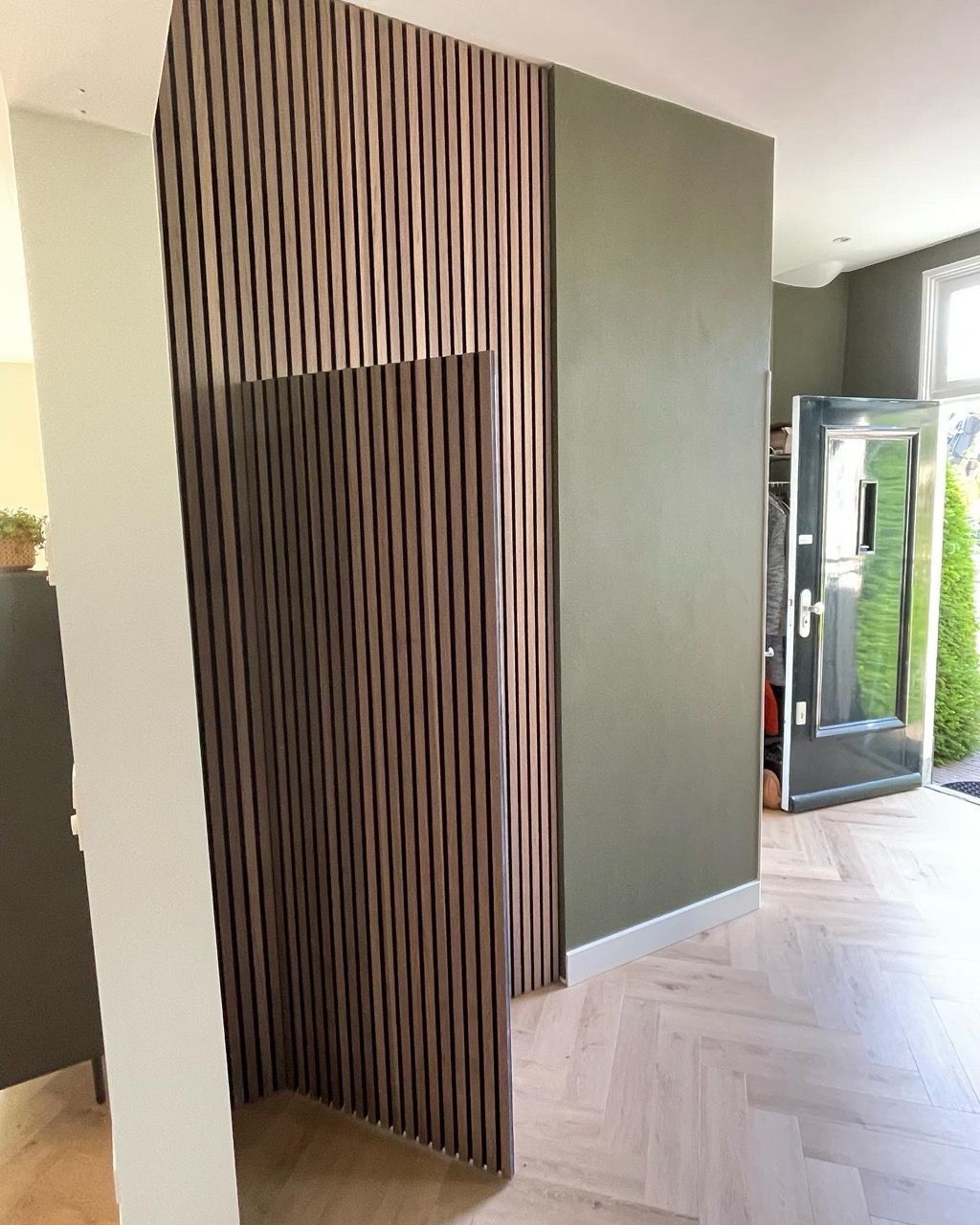 Een deel van de muur vakkundig omtimmerd met akoestische panelen door Vuijst & Vuijst, verbeterend de geluidskwaliteit in de ruimte terwijl het een esthetische toevoeging biedt aan het interieur