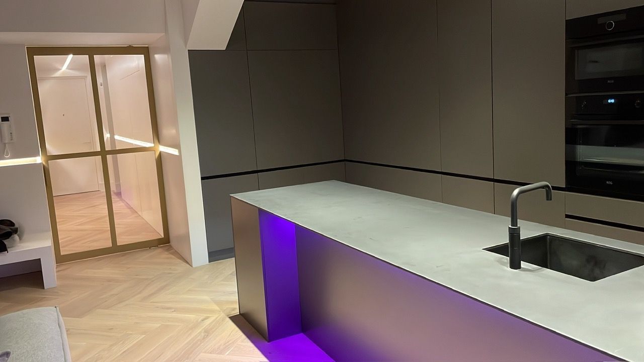 Een keuken met een paars licht op het aanrecht en een gootsteen.