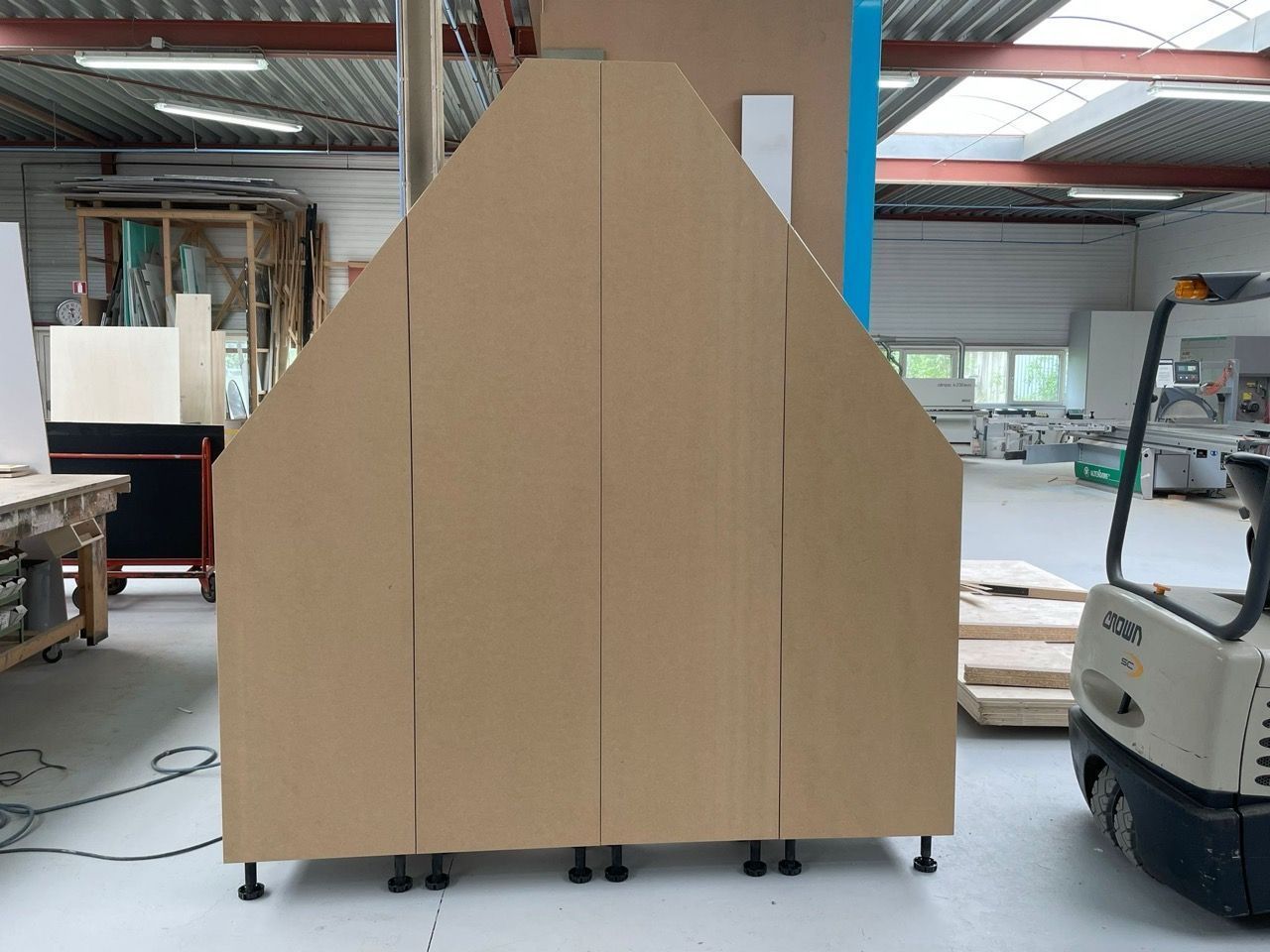 Een vorkheftruck verplaatst een stuk hout in een fabriek.