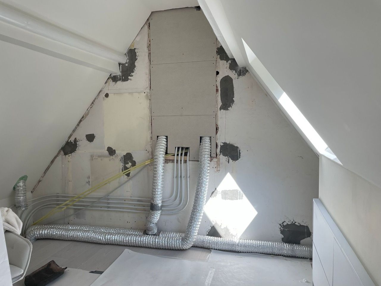 Een kamer met een schuin plafond en een raam