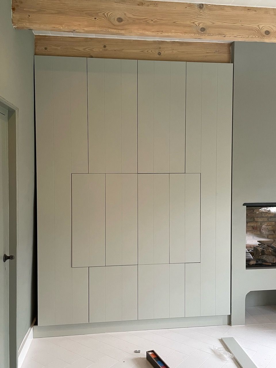 Een naadloos ontworpen kledingkast met drukdeuren en zonder zichtbare handgrepen door Vuijst & Vuijst, volledig geïntegreerd in de ruimte voor een strakke en moderne uitstraling.