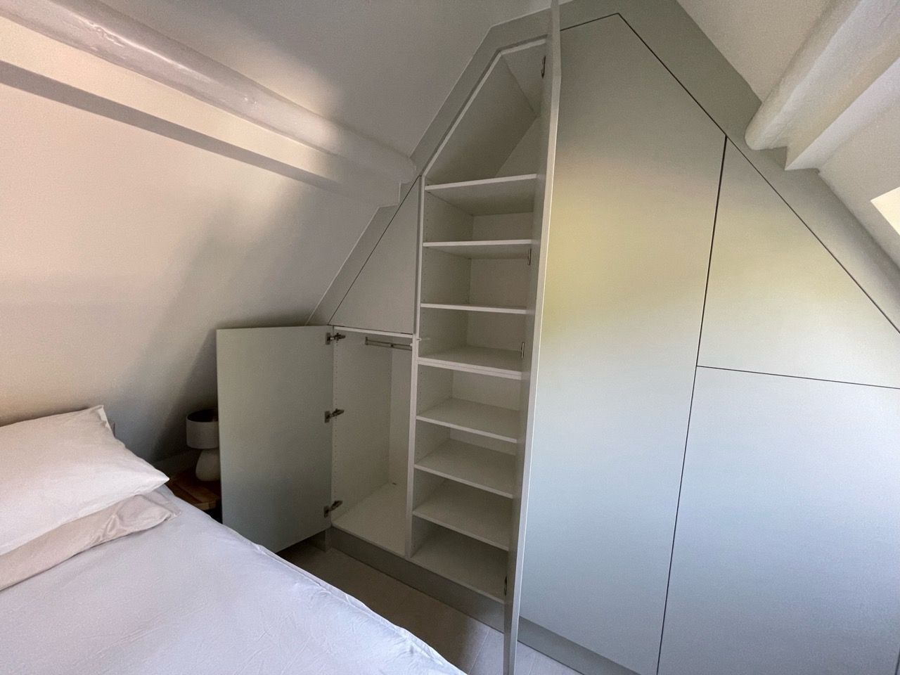 Een slaapkamer met een bed en een kast op zolder.