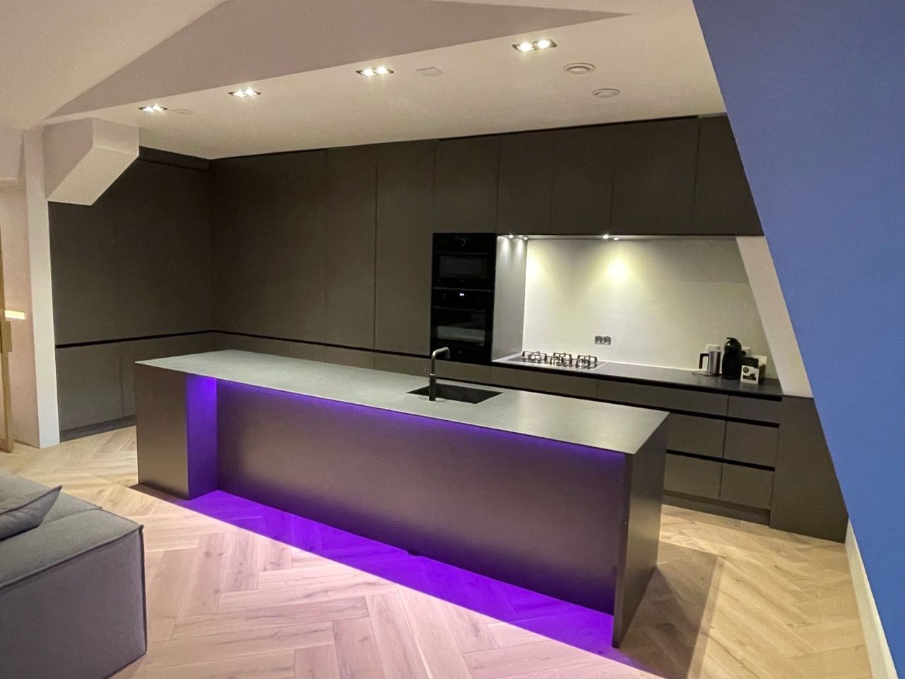 Een keuken met een groot kookeiland en paarse lampen.