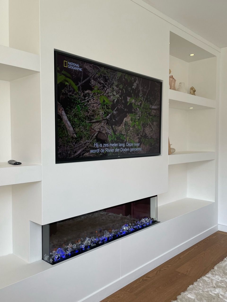 Een woonkamer met een open haard en een flatscreen-tv aan de muur.